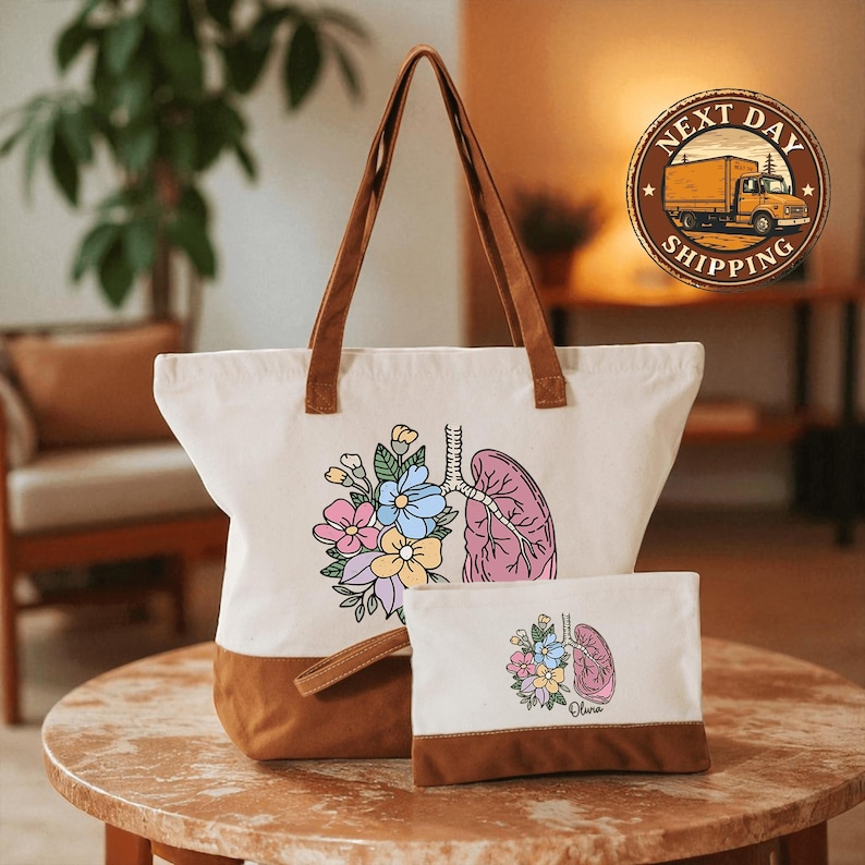 A white tote bag with a floral design and a smaller bag with a similar floral design are displayed on a wooden table.