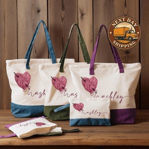 May include: Cream-colored tote bags and pouches with a heart-shaped yarn design and personalized names. The bags have colored bottoms and handles in blue, green, and purple. The image also includes a "Next Day Shipping" graphic.