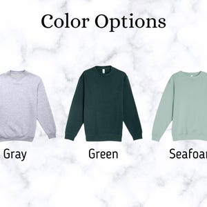 May include: Image showing three crewneck sweatshirts in different colors: gray, green, and seafoam. The text "Color Options" is at the top. Below each sweatshirt is the color name: "Gray", "Green", and "Seafoam".