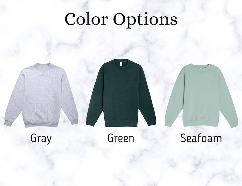 May include: Image showing three crewneck sweatshirts in different colors: gray, green, and seafoam. The text "Color Options" is at the top. Below each sweatshirt is the color name: "Gray", "Green", and "Seafoam".