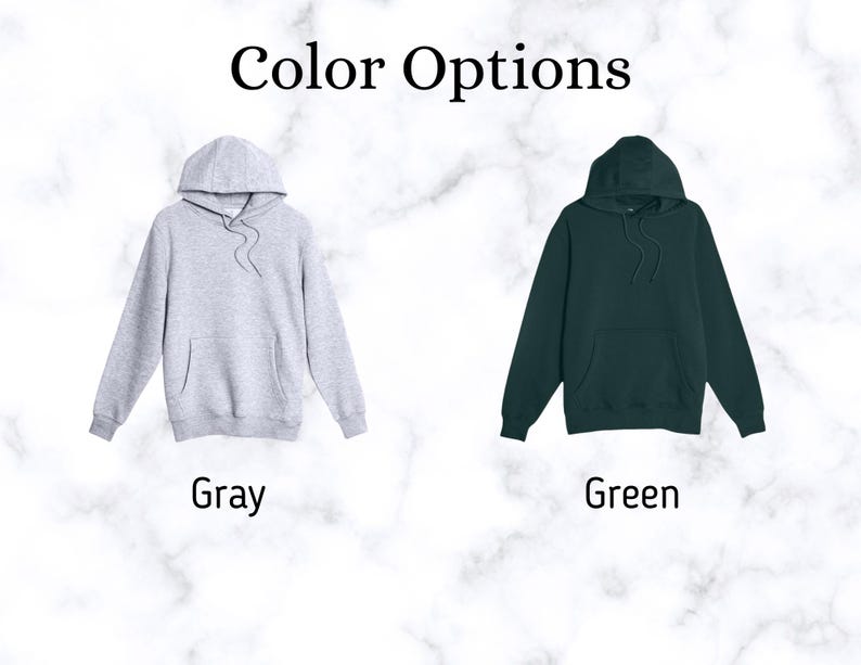 May include: Two hooded sweatshirts in gray and green are displayed against a marble background. The text "Color Options" is at the top. The gray hoodie is on the left, and the green hoodie is on the right. The word "Gray" is below the gray hoodie, and the word "Green" is below the green hoodie.
