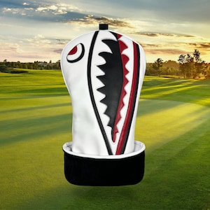 Op de afbeelding: Witte golfclubhoofdbeschermer met een haaienontwerp. De hoes heeft een witte buitenkant met zwarte en rode accenten, waaronder een haaienbek en oog. De onderkant is zwart.