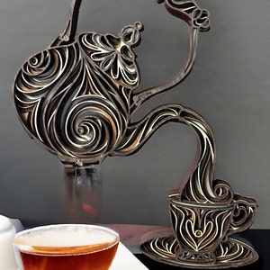 May include: A wooden decorative sculpture of a teapot pouring tea into a cup. The teapot and cup are intricately carved with swirling patterns. The sculpture is painted in shades of brown, black, and white.