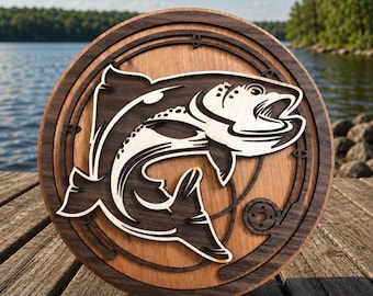 May include: A circular wooden wall art piece featuring a layered design of a jumping fish in the center. The artwork is constructed from light and dark wood tones, showcasing a detailed silhouette of a fish surrounded by a fishing rod motif.