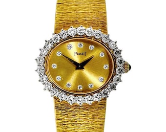 May include: A gold-toned wristwatch with a textured band and an oval face. The watch face is gold with diamond hour markers and black hands. The bezel is encrusted with diamonds. The watch is a luxury item.
