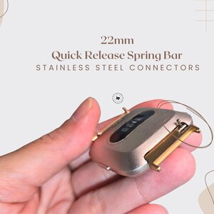 Puede incluir: Primer plano de una barra de resorte de liberaci&oacute;n r&aacute;pida de 22 mm con conectores de acero inoxidable. El componente del reloj es de color oro y plata. El texto "22mm Quick Release Spring Bar Stainless Steel Connectors" es visible.