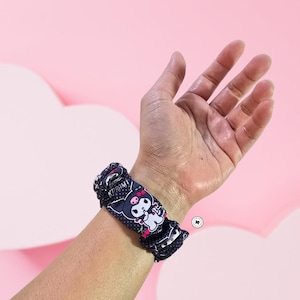 May include: A black and white watch band with a cartoon character design. The band is made of fabric and has a stretchy fit.