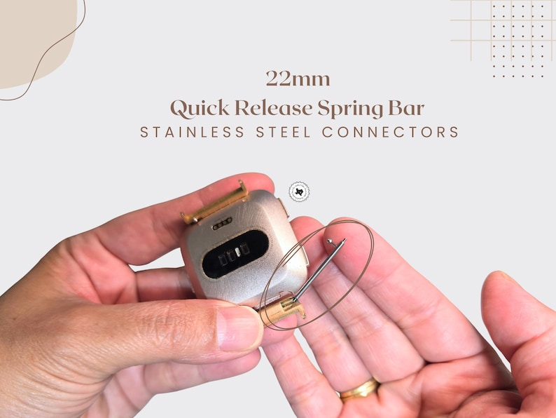 Puede incluir: Primer plano de un componente de reloj con el texto "22mm Quick Release Spring Bar Stainless Steel Connectors". El componente del reloj es plateado con un cierre dorado. Se sostiene una fina barra de resorte de metal curvada.