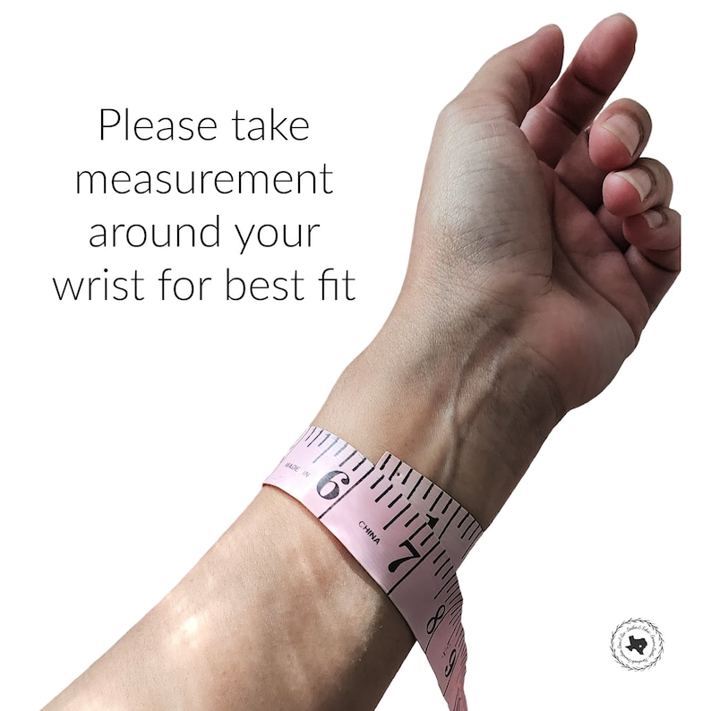 May include: A pink flexible measuring tape wrapped around a wrist with the text Please take measurement around your wrist for best fit. The tape shows black markings and numbers including 6 and 7, indicating measurements in inches for sizing.