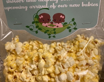 May include: A thank you bag filled with popcorn for a baby shower. The bag has a tag that says "Thank you for coming to my baby shower and helping celebrate the upcoming arrival of our new babies". The tag features two cartoon babies in a pea pod.