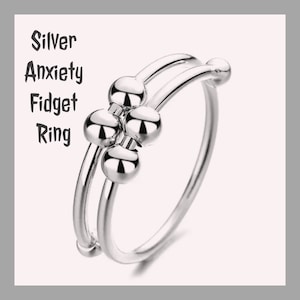 May include: Silver anxiety fidget ring with four spinning balls. The ring is made of silver and has a polished finish.