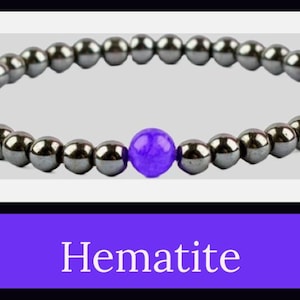 Può includere: Braccialetto in ematite con piccole perline grigio scuro e una perla centrale viola vibrante. La parola "Hematite" è visualizzata in testo bianco su sfondo viola.