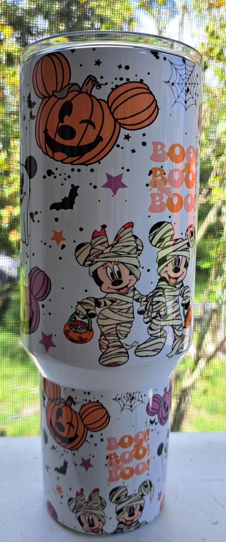 Puede incluir: Vaso blanco con tem&aacute;tica de Halloween. Presenta calabazas naranjas, murci&eacute;lagos, estrellas y las palabras "Boo!" en naranja. Incluye personajes de dibujos animados disfrazados de momias. Un dise&ntilde;o festivo y divertido.
