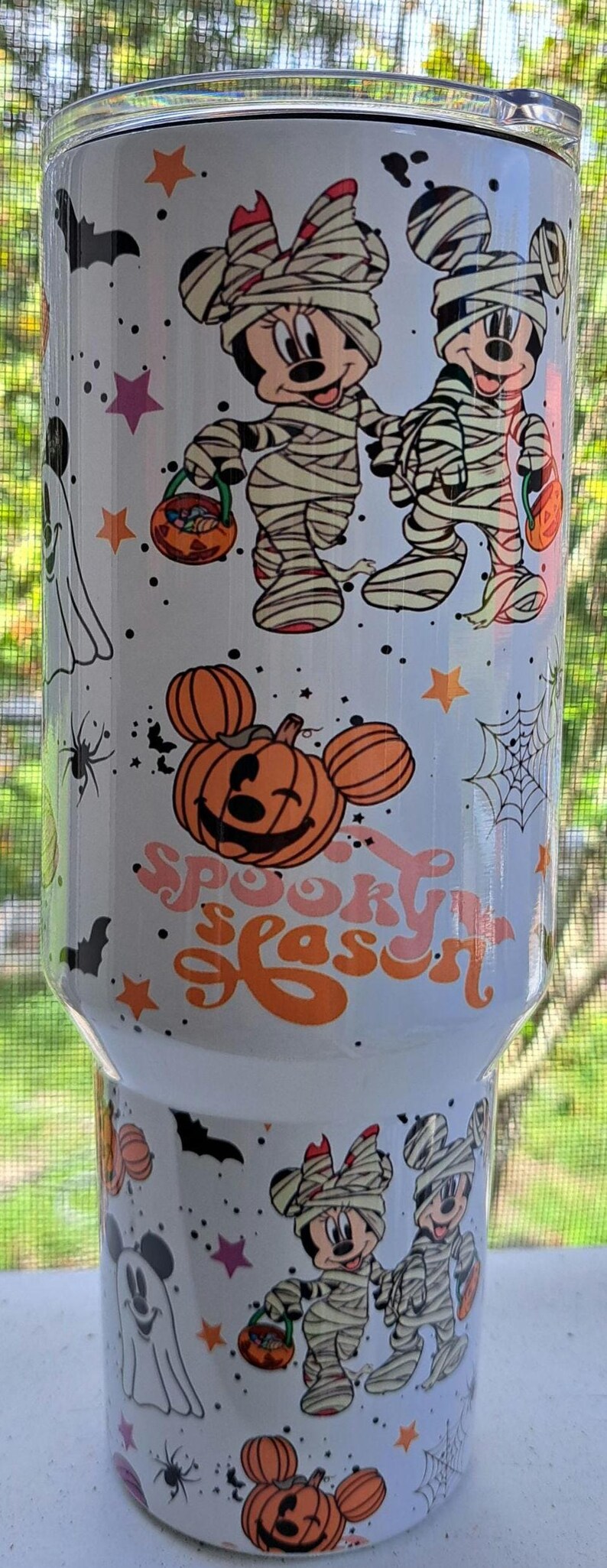 Puede incluir: Vaso blanco con gr&aacute;ficos tem&aacute;ticos de Halloween. El dise&ntilde;o incluye a Mickey y Minnie Mouse disfrazados de momias, calabazas, murci&eacute;lagos, estrellas y telara&ntilde;as. El texto "Spooky Season" tambi&eacute;n se muestra en naranja y rosa.