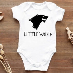 May include: White baby onesie with a black wolf graphic and the text "LITTLE WOLF" printed on the front.