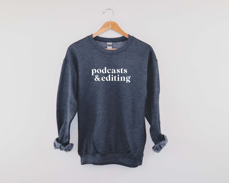 K&ouml;nnte beinhalten: Ein dunkelgrauer Pullover mit dem Aufdruck "podcasts & editing" in Wei&szlig; auf der Vorderseite.