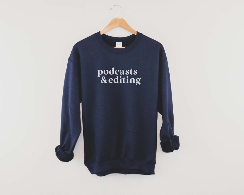 K&ouml;nnte beinhalten: Ein marineblauer Pullover mit dem Aufdruck "podcasts & editing" in Wei&szlig; auf der Vorderseite.