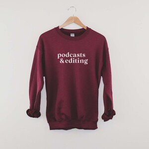 K&ouml;nnte beinhalten: Ein weinroter Pullover mit dem Text "podcasts & editing" in Wei&szlig;.