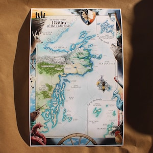 May include: A fantasy map titled "Realm of the Elderlings" with detailed illustrations of landscapes, seas, and islands. The map features text labels for locations like "Glacier Plains" and "Spice Islands," and is bordered by fantasy creatures.