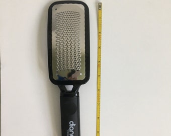 May include: A black foot file with a silver metal grater surface. The file is approximately 8 inches long. The handle has the brand name "diane" printed on it. A yellow measuring tape is next to the file.