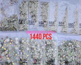 May include: Clear plastic bags filled with various sizes of iridescent rhinestones. The bags are labeled with sizes SS12, SS10, SS8, SS6, SS5, SS4, SS3, SS40, SS34, SS30, and SS20. The text "JENNIFER BEAUTY SUPPLY" and "1440 PCS" are visible.