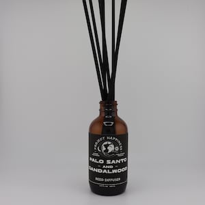May include: A brown glass reed diffuser bottle with black reeds. The bottle has a label with the text "Project Happiness Palo Santo and Sandalwood Reed Diffuser". The diffuser is 3.3 fl oz.