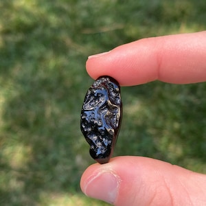 May include: A black, irregularly shaped, shiny rock with a rough, textured surface.