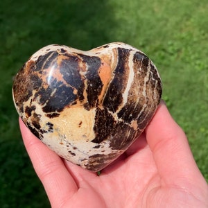 May include: A heart-shaped polished stone with brown, white, and orange marbling.