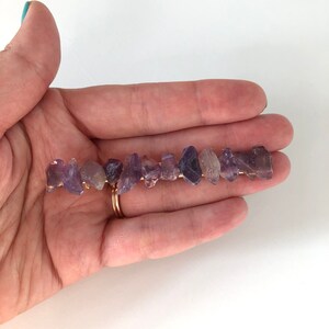 May include: A gold wire hair clip with a row of small, irregular amethyst stones.