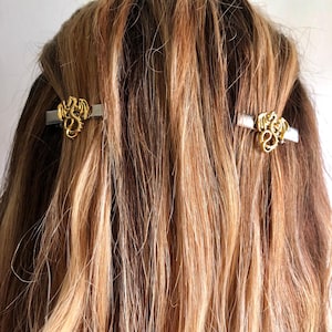 May include: Two gold dragon hair clips are set in the hair. The detailed dragons are mounted on silver bars. The hair is a mix of blonde and brown shades.