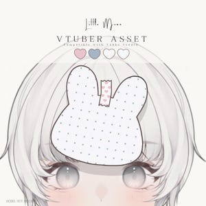 Könnte beinhalten: Ein digitales VTuber-Asset, das ein weißes, hasenförmiges Haar-Accessoire mit blauen Punkten zeigt, befestigt mit einem kleinen Stück rosa Klebeband mit Herzmuster. Der Text Little Moon VTUBER ASSET steht darüber mit vier Farbkreisen.