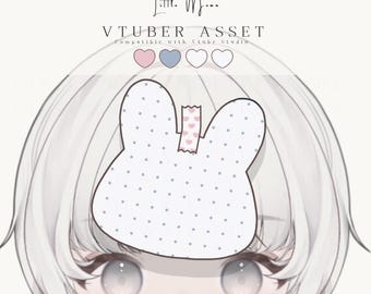 May include: A digital VTuber asset featuring a white bunny-shaped hair accessory with blue polka dots, secured by a small piece of pink heart-patterned tape. The text Little Moon VTUBER ASSET is displayed above the accessory with four color circles.