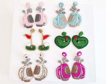 May include: A set of 10 beaded earrings featuring golf-themed designs. The earrings are made with colorful beads and feature golf bags, golf balls, and golf flags.