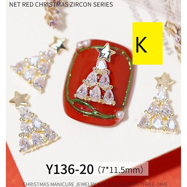 Pode incluir: Quatro pingentes de unha de &aacute;rvore de Natal dourados com strass transparentes. Os pingentes medem 7 mm por 11,5 mm e s&atilde;o etiquetados como "Y136-20".