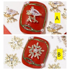 Pode incluir: Dois designs de arte de unhas com detalhes dourados e de strass. O primeiro design apresenta uma rena dourada com um strass em uma unha vermelha e verde. O segundo design apresenta um floco de neve dourado com um strass em uma unha vermelha e verde.