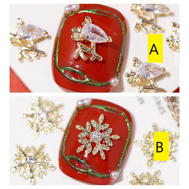 Pode incluir: Dois designs de arte de unhas com detalhes dourados e de strass. O primeiro design apresenta uma rena dourada com um strass em uma unha vermelha e verde. O segundo design apresenta um floco de neve dourado com um strass em uma unha vermelha e verde.