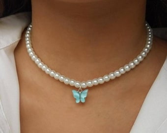 May include: A white pearl choker necklace with a light blue butterfly charm.