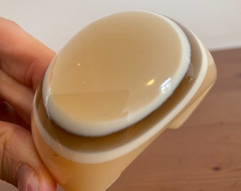 Könnte beinhalten: Ein beigefarbenes Plastik-Armband mit braunen und weißen Streifen.