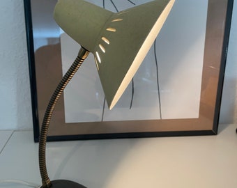 May include: A vintage green desk lamp with a flexible arm and a grey base. The lamp has a white shade with cutouts and a white cord.