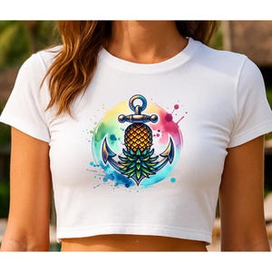May include: White crop top featuring a colorful graphic of an anchor with a pineapple in the center. The anchor is blue and gold, set against a watercolor background with rainbow hues and splashes of pink and blue.