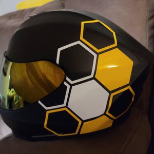 May include: Black motorcycle helmet with a honeycomb pattern in yellow, white, and black.