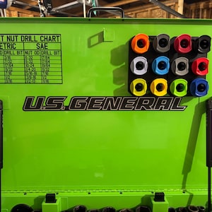 May include: A bright green U.S. General tool chest with a rivet nut drill chart and a holder with colorful tool attachments. The chart lists metric and SAE measurements. The tool chest is open, revealing its interior.
