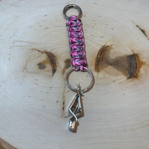May include: A pink and grey paracord keychain with a silver metal key clip.