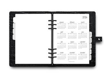 May include: Open black leather binder with a 2026 calendar displayed. The calendar pages are white with black text, showing the months and days. The binder has a textured finish and metal rings.