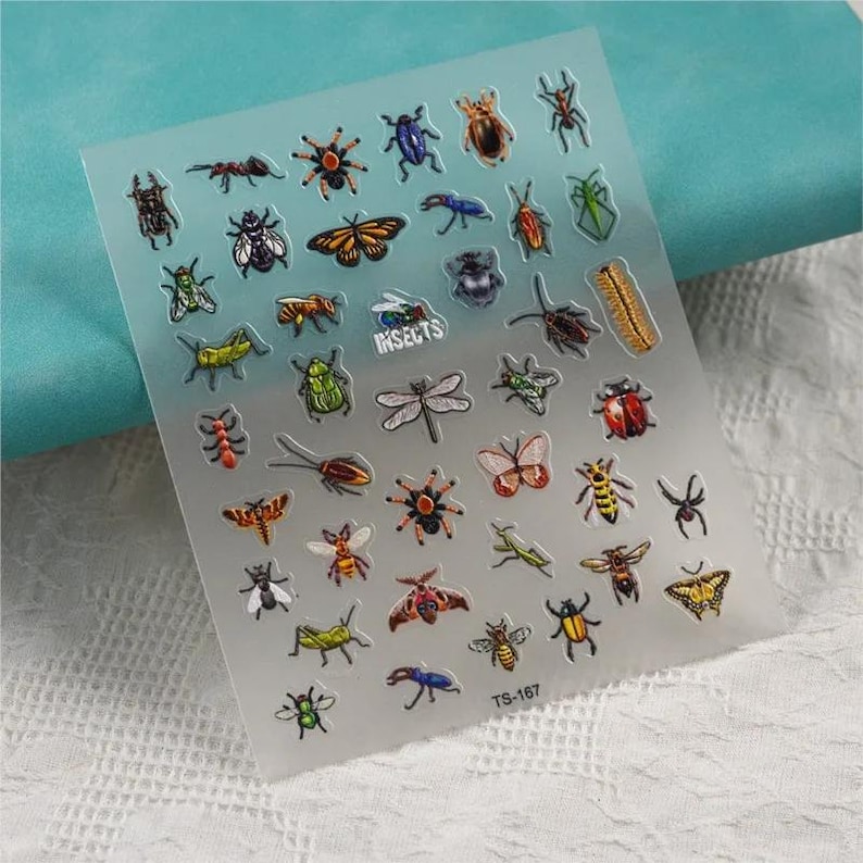 May include: A sheet of clear sticker paper with colorful insect illustrations. The stickers feature a variety of insects, including butterflies, beetles, dragonflies, and ants. The sheet is labeled "INSECTS" and "TS-167".