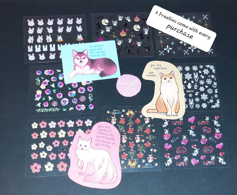 May include: Assortment of colorful stickers featuring various designs, including animals, flowers, and inspirational quotes. The stickers are arranged on a black surface. The text on the stickers reads: "No difficult days and you will get through this", "Free Gift", "You are important. You matter.", "You are capable of handling whatever life throws at you today", and "2 Freebies come with every purchase".