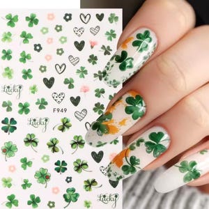 May include: Nail art stickers with green shamrocks, hearts, and flowers. The sheet includes the word "Lucky" and the number "F949". Some nails are painted with shamrock designs and orange accents.