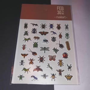 May include: A sheet of nail art stickers featuring a variety of insects, including butterflies, ladybugs, beetles, and dragonflies. The stickers are on a white background with the text "FEB 30TH WE - nailart - TS-107".