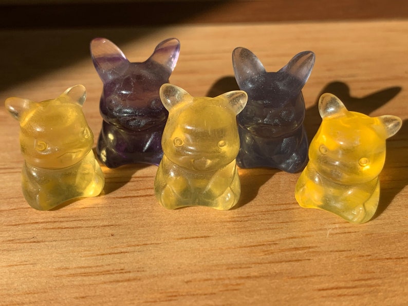 May include: Five gummy candy figurines shaped like bears. Two are yellow and three are purple.