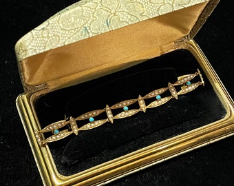 Puede incluir: Un brazalete de oro con un diseño delicado que presenta pequeños eslabones ovalados engastados con piedras turquesa. El brazalete se muestra en una caja de joyería forrada de terciopelo.
